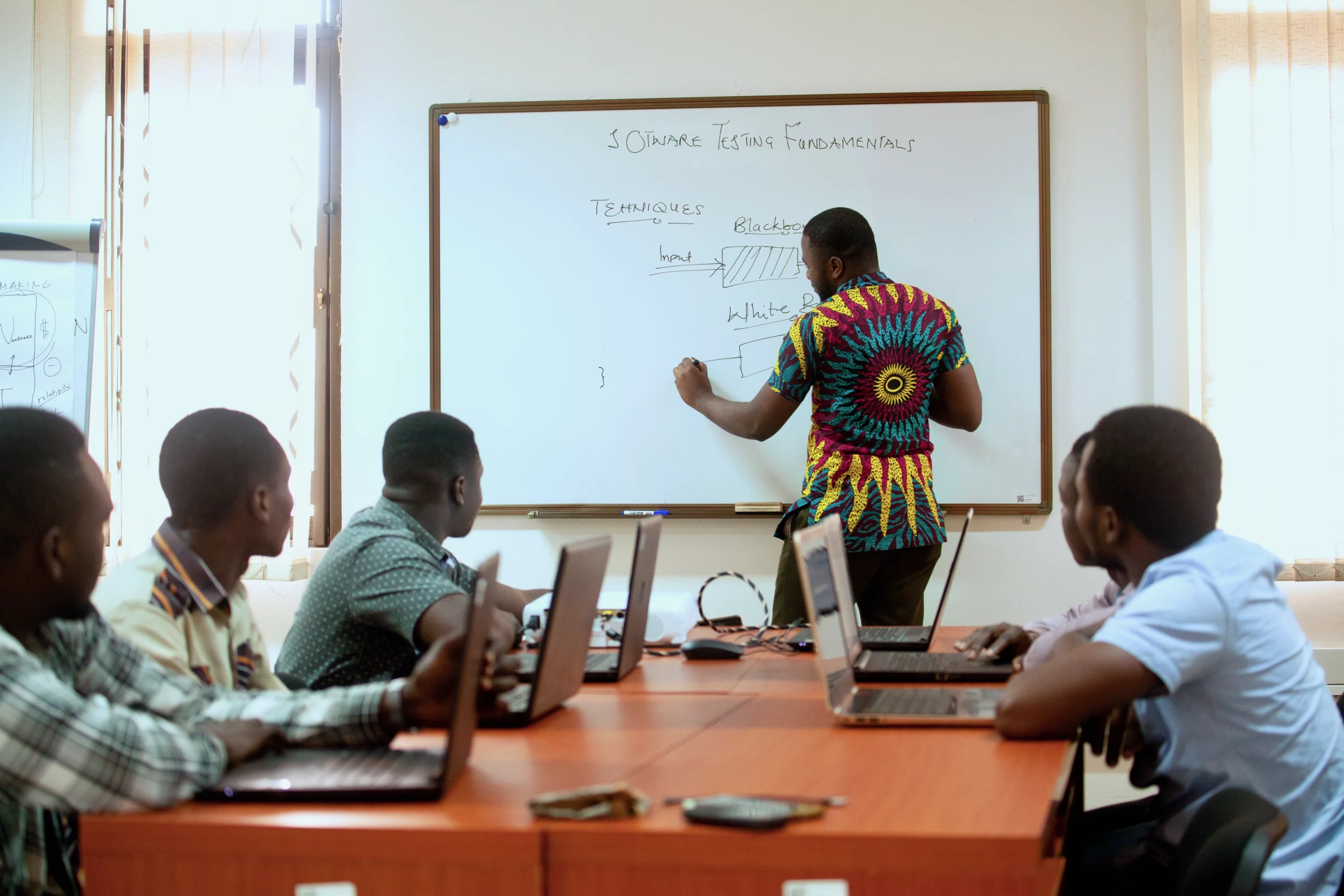 This image shows a trainer writing information about software development fundamentals on a whiteboard